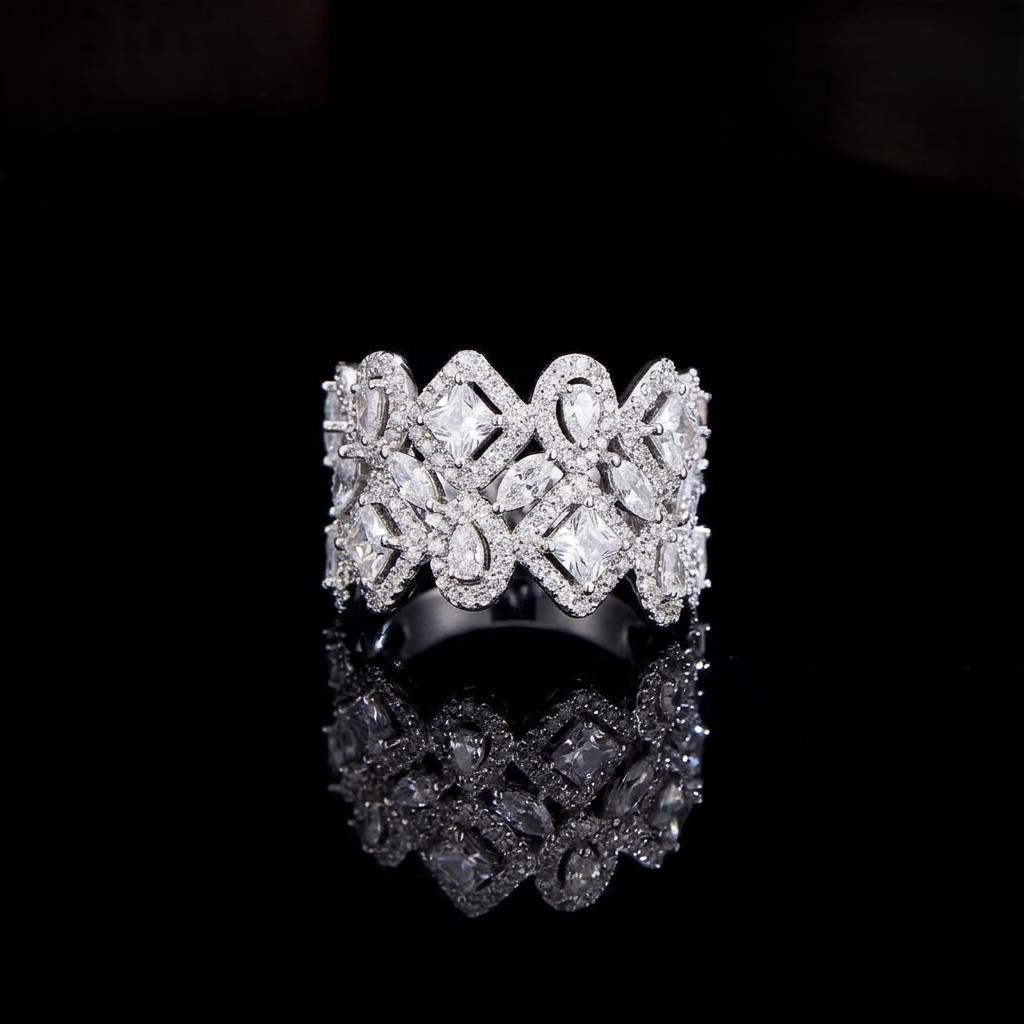 A wide, intricately designed statement ring in a sleek silver-colored finish, featuring a geometric lattice pattern filled with sparkling, clear marquise and square-cut zirconias.