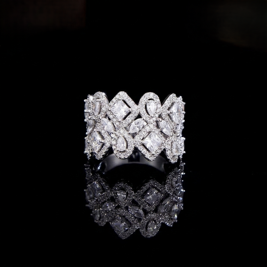 A wide, intricately designed statement ring in a sleek silver-colored finish, featuring a geometric lattice pattern filled with sparkling, clear marquise and square-cut zirconias.