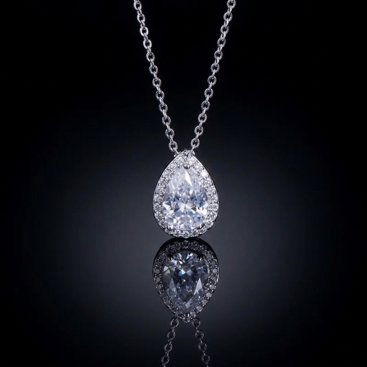 A delicate pear-shaped crystal pendant on a thin, luminous chain against a dark background, representing minimalist and sophisticated luxury style.