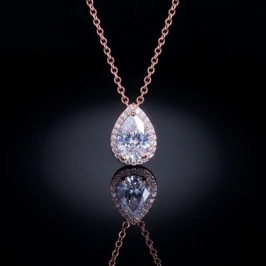 A delicate pear-shaped crystal pendant on a thin, luminous chain against a dark background, representing minimalist and sophisticated luxury style.