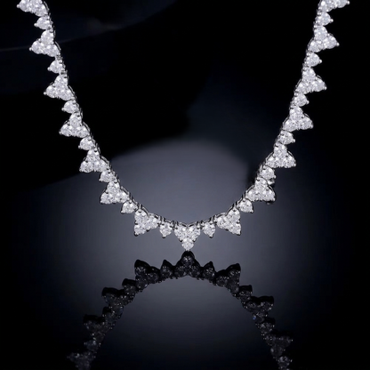 Close-up of a sparkling diamond-style necklace with heart-shaped stone settings against a professional pitch-black reflective background.