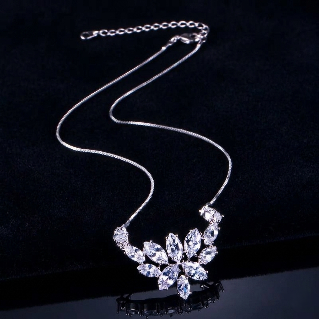 A detailed close-up photograph showcasing a delicate, silver-toned necklace lying diagonally on a deep black velvet surface, featuring an intricate central pendant shaped like a blooming lotus with multiple brilliant and marquise-cut shimmering stones, with an adjustable chain and lobster clasp mechanism visible at the top, and a soft reflection beneath.